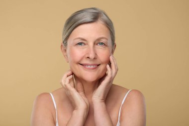 Bej arka planda yaşlanmakta olan yaşlı bir kadının portresi. Yenilenme tedavisi