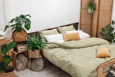 Rahat bir yatak ve yatak odasında güzel yeşil bitkiler.