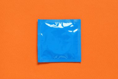 Turuncu arka planda prezervatif paketi, üst manzara. Güvenli seks.