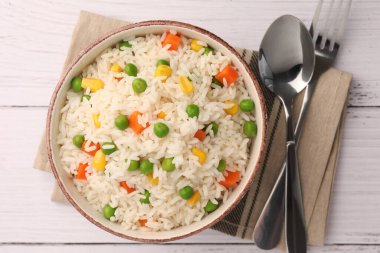 Beyaz ahşap masada servis edilen sebzeli bir kase lezzetli pirinç.