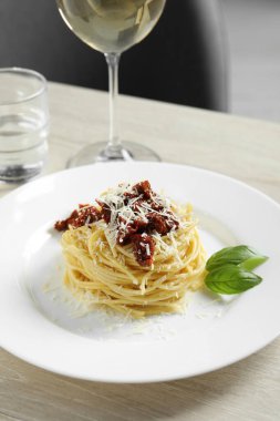 Ahşap masada servis edilen güneşte kurutulmuş domatesli ve parmesan peynirli leziz spagetti. Makarna yemeğinin enfes sunumu