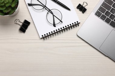 Merkez ofis. Dizüstü bilgisayar, gözlük, ev bitkisi ve kırtasiye malzemeleri beyaz ahşap masa, düz yatak. Metin için boşluk