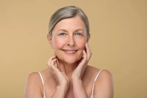 Portrait of senior woman with aging skin on beige background. Rejuvenation treatment