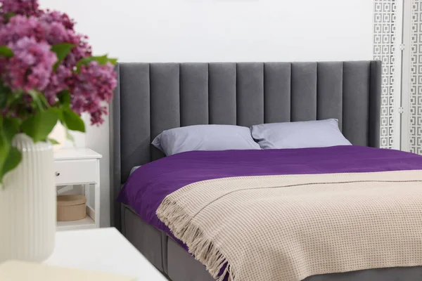 Comfortable bed with purple linens in bedroom. Interior design