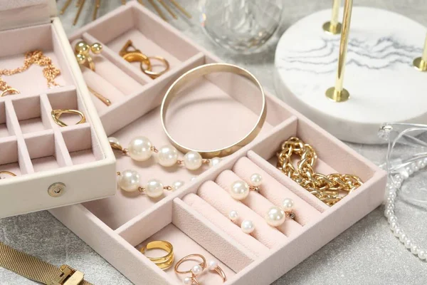 Jewelry boxes with many different accessories on light grey table, closeup
