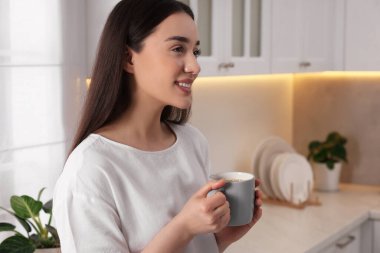 Mutfakta bir bardak içkisi olan mutlu bir kadın. Mesaj atmak için yer var. Tembel sabah