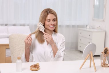 Güzel bir kadın yatak odasında saçını tarıyor.