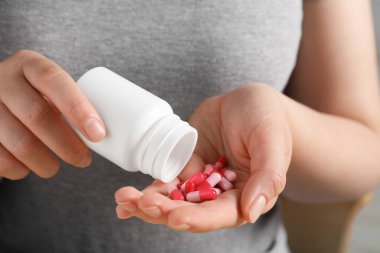 Şişeden haplar döken kadın, yakın çekim görüntüsü.