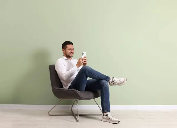 Happy Man Zitten Een Fauteuil Met Behulp Van Smartphone Buurt — Stockfoto