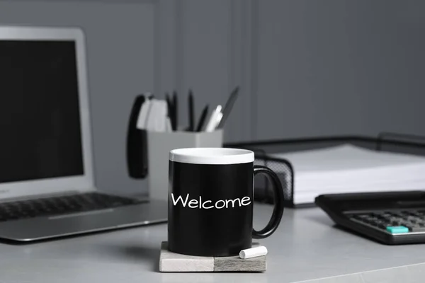 Cup with chalked word Welcome on office desk