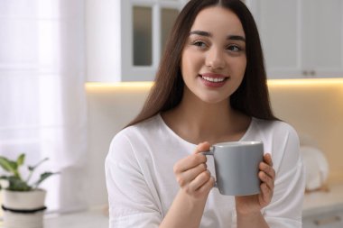 Mutfakta bir bardak içkisi olan mutlu bir kadın. Mesaj atmak için yer var. Tembel sabah