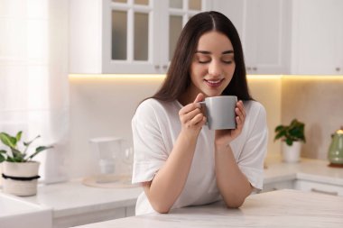 Mutfakta bir bardak içkisi olan mutlu bir kadın. Mesaj atmak için yer var. Tembel sabah