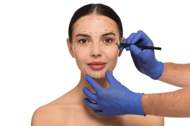 Beyaz arka planda estetik ameliyat için kalem hazırlayan bir doktor.