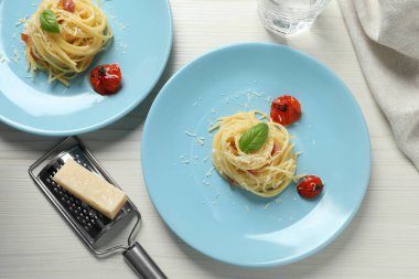 Beyaz ahşap masada servis edilen domatesli ve parmesan peynirli leziz spagetti. Makarna yemeğinin enfes sunumu