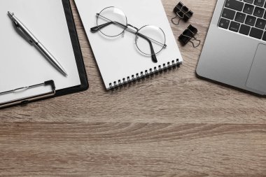 Merkez ofis. Laptop, bardaklar ve kırtasiye malzemeleri ahşap masada, düz yerde. Metin için boşluk