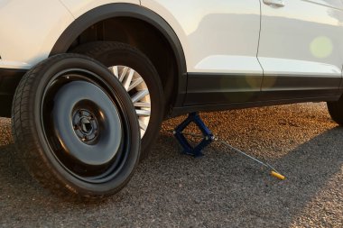 Araba yol kenarında makas kriko ve yedek tekerlekle kaldırıldı.
