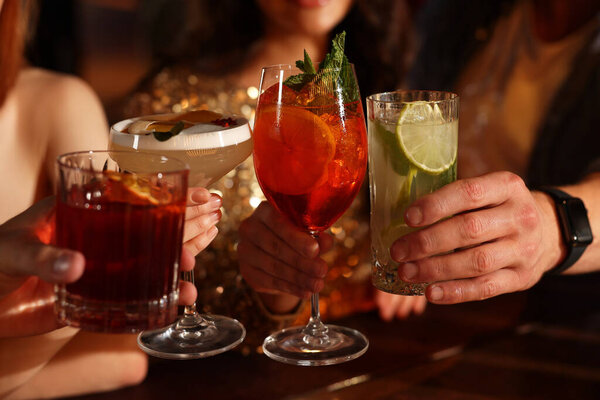 Друзья звонят в стаканы со свежими коктейлями в баре, крупным планом