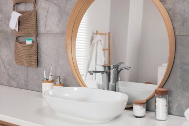 Beyaz damar lavabosu, ayna ve banyo tezgahındaki farklı kişisel bakım ürünleri. İç tasarım