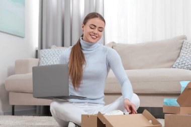 Evde dizüstü bilgisayarı olan mutlu kadın paketleri açıyor. Çevrimiçi mağaza