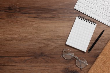 Farklı kırtasiye malzemeleri, bilgisayar klavyesi ve tahta masadaki gözlükler, mesaj için yeri olan düz bir yer. Merkez Ofis