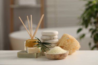 Banyodaki beyaz masanın üzerinde farklı spa ürünleri ve palmiye yaprakları olan kompozisyon