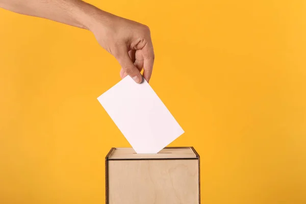 Mann Legt Seine Stimme Wahlurne Auf Gelbem Hintergrund Nahaufnahme — Stockfoto