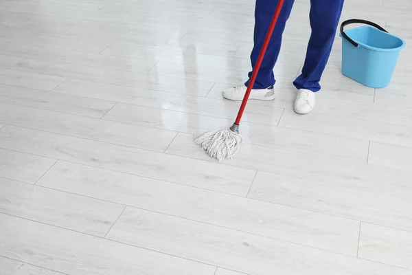 Man cleaning floor with mop indoors, closeup. Space for text