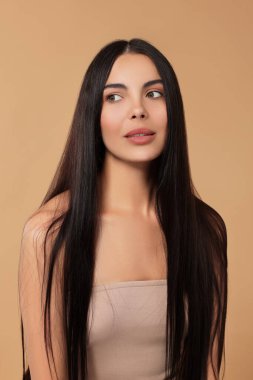 Bej arka planda uzun saçlı güzel bir kadın.