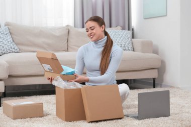 Evde paketleri açan mutlu kadın. Çevrimiçi mağaza