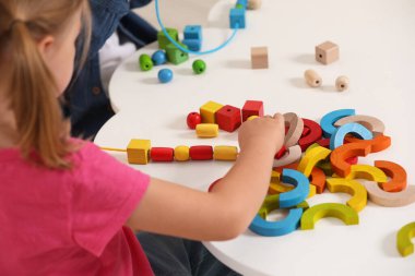 Küçük çocuklar ahşap parçalarla oynuyorlar ve beyaz masa içerisindeki iplik aktivitesi için, yakın plan. Gelişimsel oyuncaklar