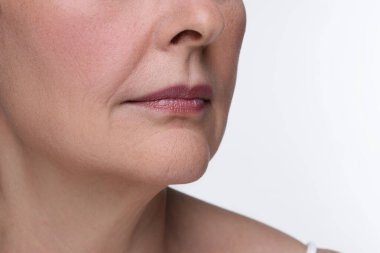 Beyaz arka planda yaşlanan yaşlı bir kadın, yakın plan. Yenilenme tedavisi