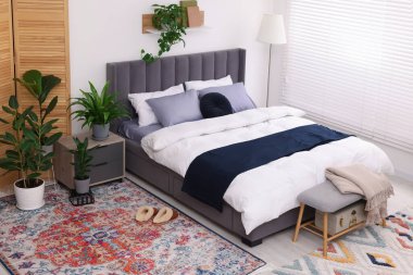 Çift kişilik yatağı ve güzel yeşil çiçekleri olan şık bir yatak odası. Modern iç mimari