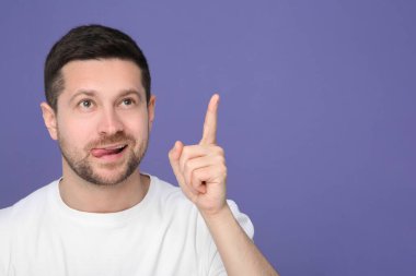 Adam dilini gösteriyor ve mor arka plandaki bir şeye işaret ediyor. Metin için boşluk