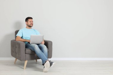 Dizüstü bilgisayarı olan mutlu bir adam içerideki koltukta oturuyor, mesaj için yer var.