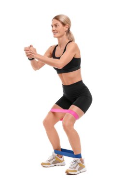 Beyaz arka planda elastik direnç bandıyla egzersiz yapan kadın.