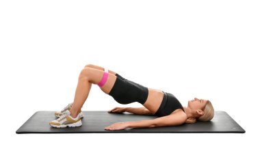 Beyaz arkaplana karşı fitness minderi üzerinde elastik direnç bandıyla egzersiz yapan kadın