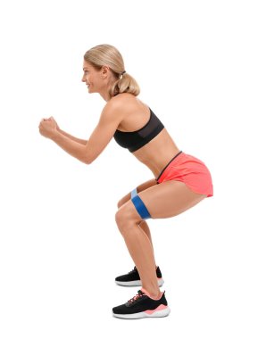 Beyaz arka planda elastik direnç bandıyla egzersiz yapan kadın.