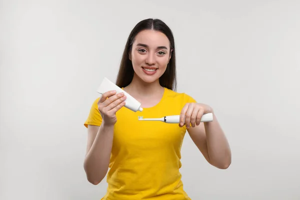 Szczęśliwa Młoda Kobieta Wyciskająca Pastę Zębów Tuby Elektryczną Szczoteczkę Zębów — Zdjęcie stockowe