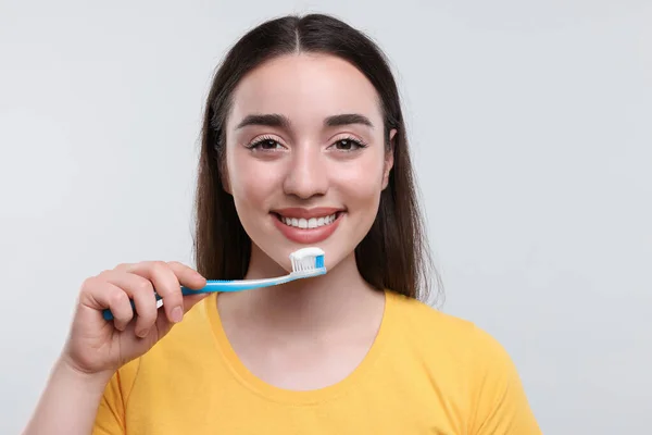 stock image Happy young woman holding plastic toothbrush on white background