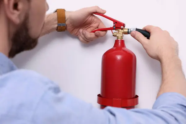 stock image Man checking quality of fire extinguisher indoors, closeup