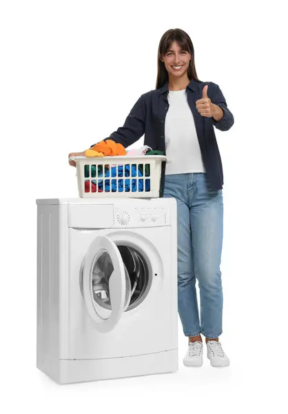 白い背景の洗濯機の近くに親指を示す洗濯バスケットが付いている美しい女性 — ストック写真