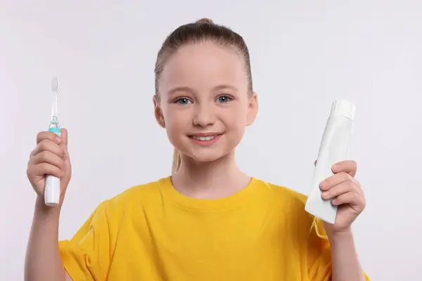 Ευτυχισμένο Κορίτσι Κρατώντας Ηλεκτρική Οδοντόβουρτσα Και Σωλήνα Οδοντόκρεμας Λευκό Φόντο — Φωτογραφία Αρχείου