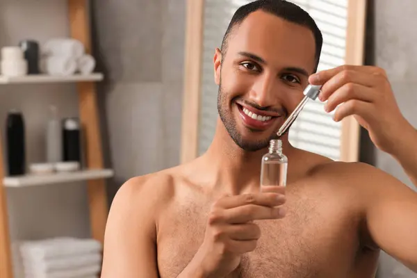 Knappe Man Met Cosmetisch Serum Handen Badkamer Ruimte Voor Tekst — Stockfoto