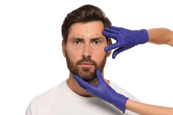 stock image Doctor checking patient's face before cosmetic surgery operation on white background