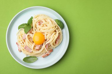 Açık yeşil arka planda yumurta sarısı ile nefis bir Carbonara makarna, üst manzara. Metin için boşluk