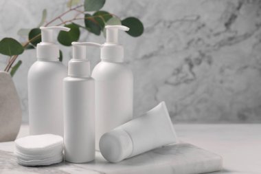 Beyaz masada farklı yüz temizleme ürünleri ve pamuk pedler. Metin için boşluk