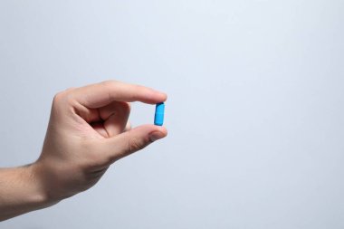 Açık gri arka planda hapları tutan adam, yakın plan. Metin için boşluk