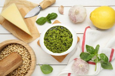 Lezzetli pesto sosu kasede ve malzemeler beyaz ahşap masada, düz yerde.