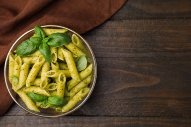 Pesto soslu lezzetli makarna ve ahşap masada fesleğen, üst manzara. Metin için boşluk
