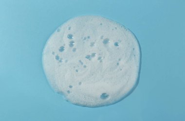 Açık mavi arka planda köpük temizleme örneği, üst görünüm. Kozmetik ürünü